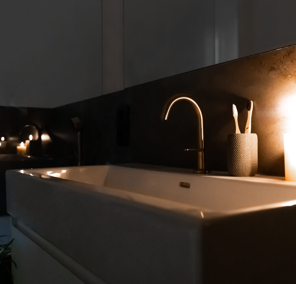 Badezimmer Melbourne: Ausschnitt zeigt Waschbecken mit goldfarbener Armatur in Kerzenschein.