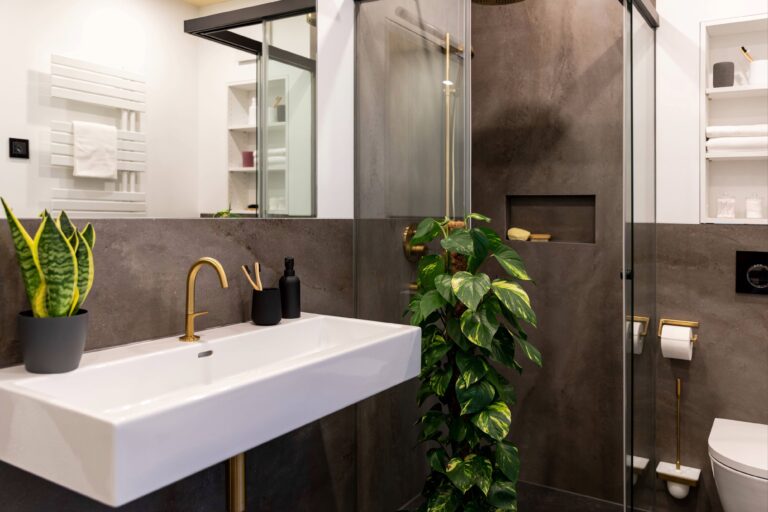 Badezimmer Melbourne: Ausschnitt zeigt WC, Dusche und Waschbecken mit goldfarbener Armatur.